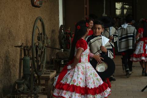 Una pareja de niños vestida con trajes tradicionales conversan en un entorno rural.