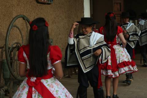 Un grupo de niños vestidos con trajes tradicionales están bailando en un entorno rural.