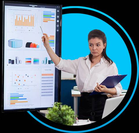 Una mujer señala una pantalla con gráficos y datos en una oficina.