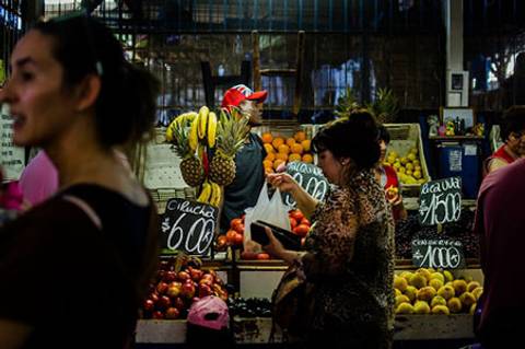 Una escena vibrante en un mercado con frutas variadas y compradores.