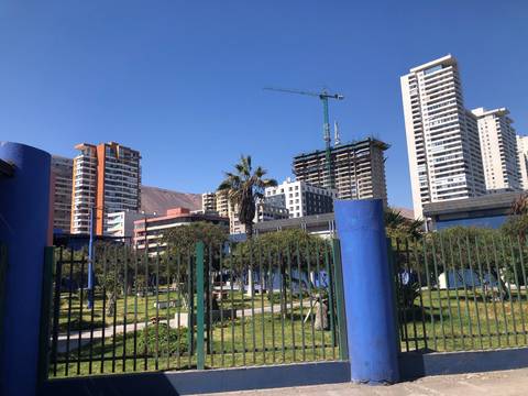 Una vista de un parque con edificios altos y una grúa en construcción al fondo.
