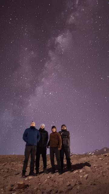 Cuatro amigos posando bajo un cielo estrellado en el desierto chileno.