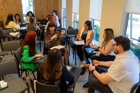 Un grupo de personas conversando en una sala durante una reunión o taller.