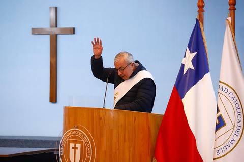 Un hombre en una ceremonia religiosa levanta la mano mientras se encuentra frente a un podio con símbolos chilenos.