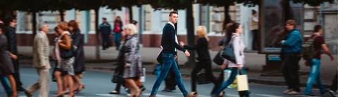 Un hombre camina por la calle rodeado de un grupo de personas.