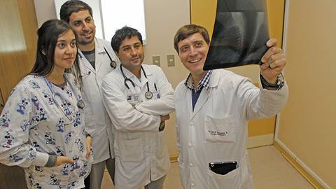 Cuatro profesionales de la salud observan una radiografía en un ambiente clínico.