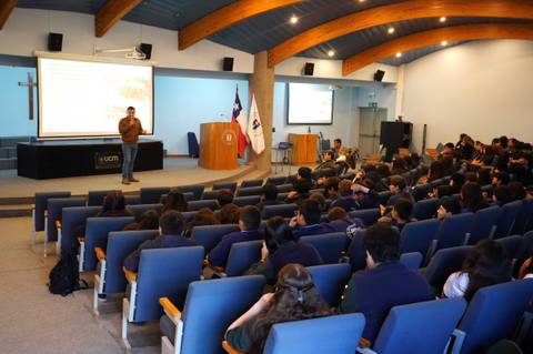 Un profesor dando una charla a un grupo de estudiantes en una sala amplia.