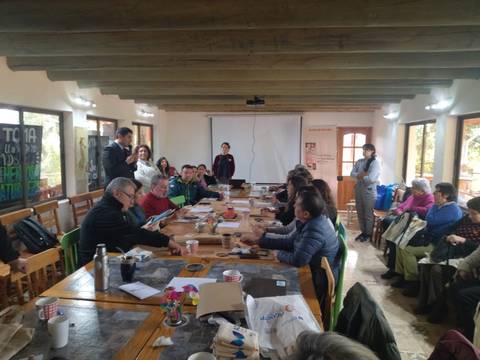 Una reunión comunitaria en un salón donde hay gente participando en actividades.