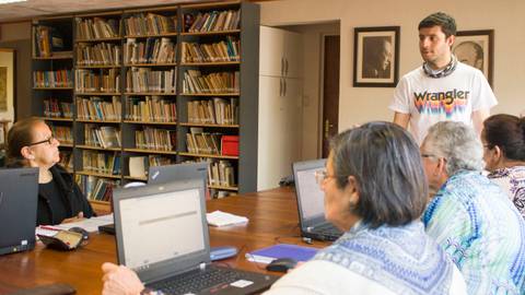 Un grupo de personas está participando en una reunión en una sala con estanterías de libros.