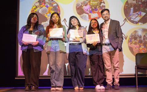 Un grupo de personas sosteniendo certificados en un evento de premiación.