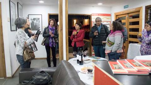 Un grupo de personas asiste a una reunión social en un ambiente acogedor, conversando y disfrutando de bebidas.