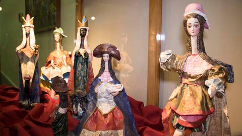 Una colección de muñecas tradicionales en una vitrina, vestidas con trajes coloridos.