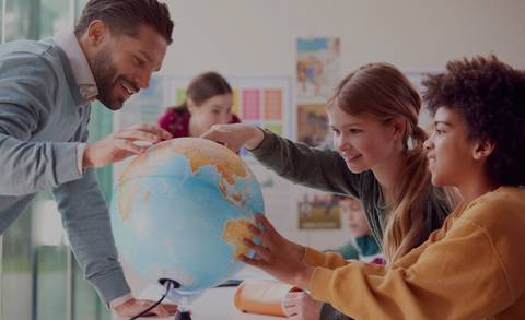 Un grupo de estudiantes interactúa con un globo terráqueo en un aula.