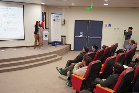 Una presentación en una sala con un ponente y público atento.