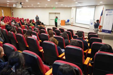 Una charla en un auditorio con varias personas sentadas y un presentador en la parte delantera.