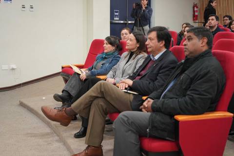 Un grupo de personas sentadas en una sala, mirando atentamente hacia el frente.