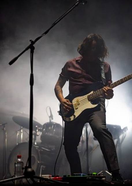 Un músico tocando el bajo en un escenario con un ambiente de neblina.