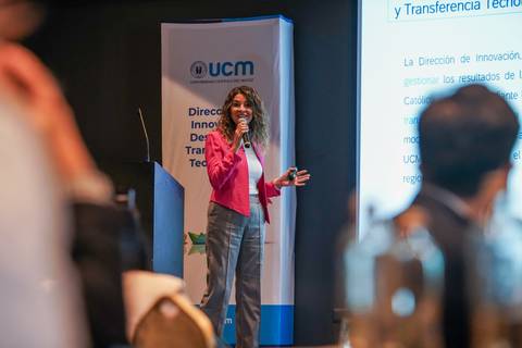 Una mujer con cabello rizado presenta en una conferencia sobre innovación y transferencia tecnológica.