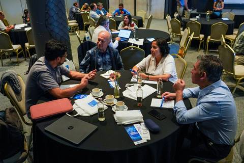 Un grupo de personas conversando en una mesa durante un evento en un salón.