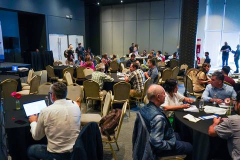 Un grupo de personas participando en un evento o conferencia en un salón amplio.
