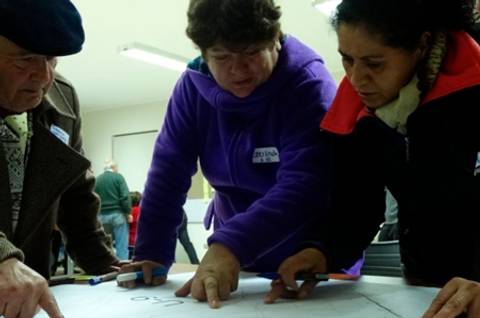 Un grupo de personas colabora en la creación de un proyecto, señalando en una hoja mientras se encuentran en un ambiente de trabajo.
