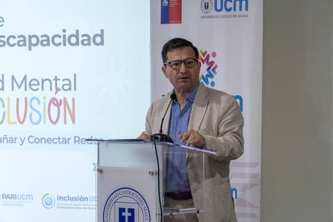 La imagen muestra a un hombre hablando en un evento sobre inclusión y discapacidad mental.
