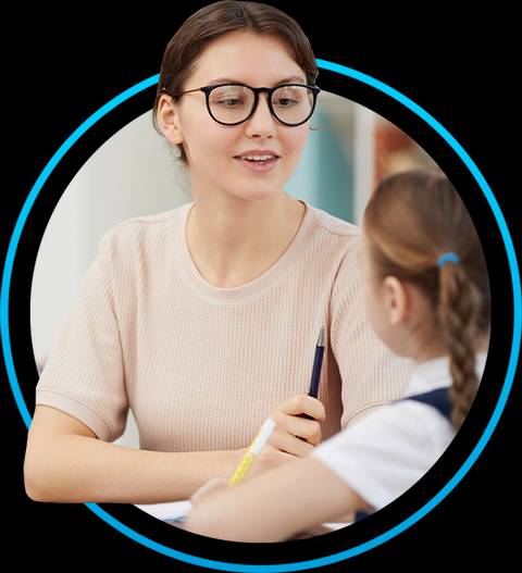 Una persona joven con gafas habla con una niña en un entorno educativo.