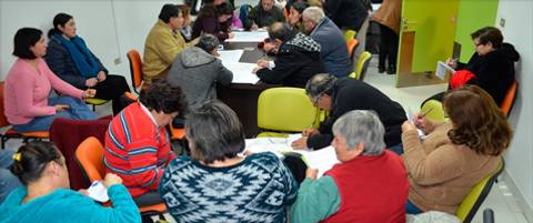 Un grupo de personas se reúne alrededor de una mesa en un ambiente de trabajo colaborativo.