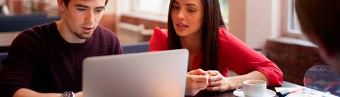 Dos personas conversando frente a un ordenador portátil en un ambiente relajado.