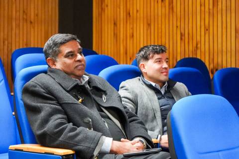 Dos hombres sentados en un auditorio frente a un público.