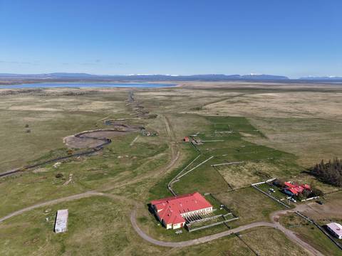 Una vista aérea de un paisaje natural con campos verdes y una construcción roja en el centro.