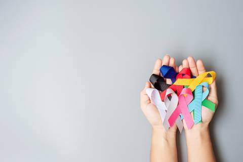 Unas manos sosteniendo cintas de distintos colores que simbolizan diversas causas y concientización.
