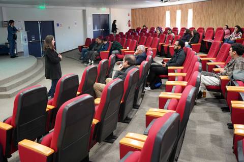 Una expositoria está hablando frente a un grupo de personas en un auditorio.
