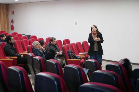 Una mujer está presentando frente a un grupo de personas en una sala de clases.