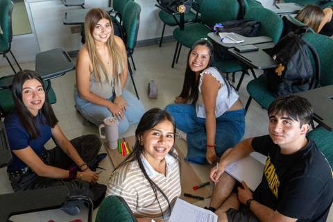 Un grupo de estudiantes se reúne en un aula para estudiar y compartir ideas.