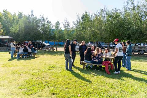 Un grupo de personas se reúne al aire libre en un día soleado, disfrutando de un momento de convivencia en la naturaleza.
