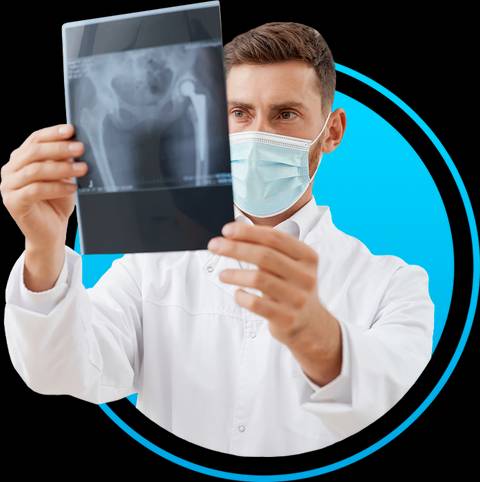 Un médico está sosteniendo una radiografía de cadera mientras usa una mascarilla.