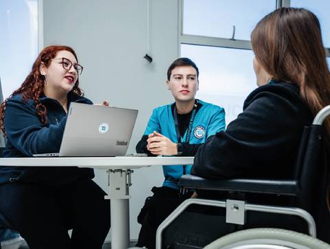 Un grupo de tres personas conversando en una oficina moderna.