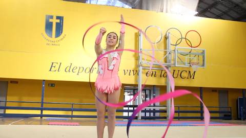 Una gimnasta realiza una rutina con cintas en un ambiente deportivo.