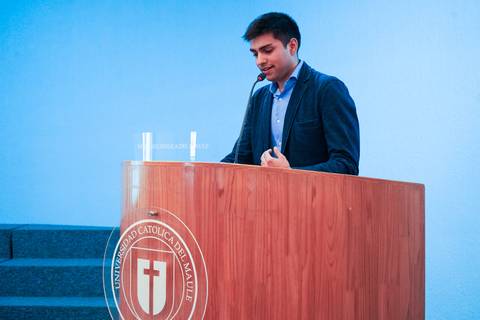 Un joven presenta en un podio en la Universidad Católica del Maule.