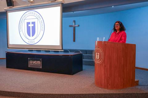 Una presentadora habla frente a un auditorio en la Universidad Católica de Maule.