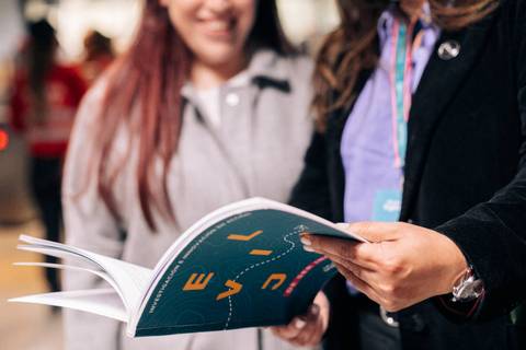 Dos personas están mirando un libro en un evento o feria.
