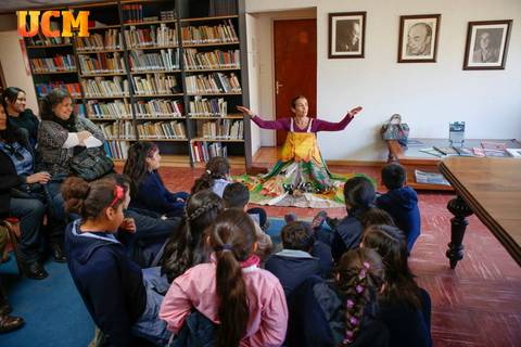 Una narradora cuenta una historia ante un grupo de niños en un ambiente de biblioteca.