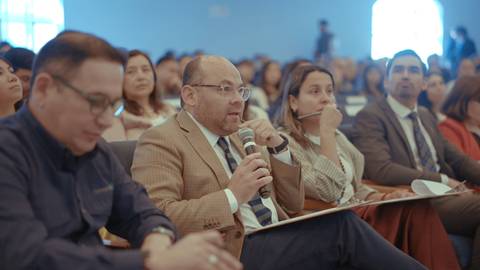 En una charla, un hombre pregunta mientras los demás asistentes lo escuchan atentamente.