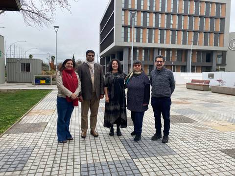 Grupo de personas sonrientes posando frente a un edificio moderno en un día nublado.