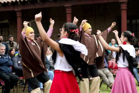 Un grupo de personas baila al aire libre, mostrando trajes tradicionales y expresando alegría en una celebración cultural.