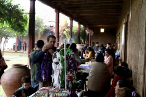 Una feria artesanal con personas comprando y vendiendo productos en un espacio al aire libre.