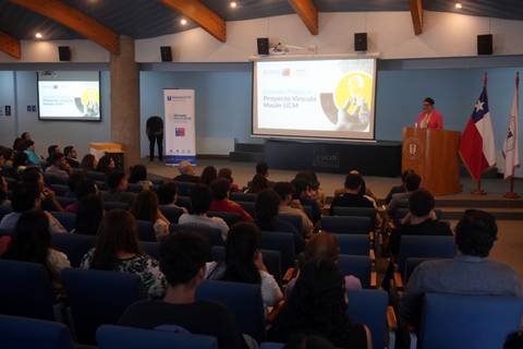 Un evento en el que una mujer presenta un proyecto frente a un público atento en un auditorio chileno.