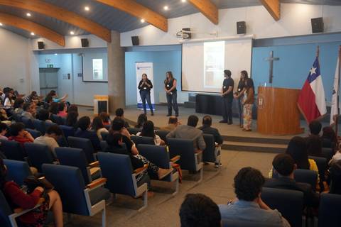 Un grupo de jóvenes presenta un proyecto en un auditorio lleno de gente.