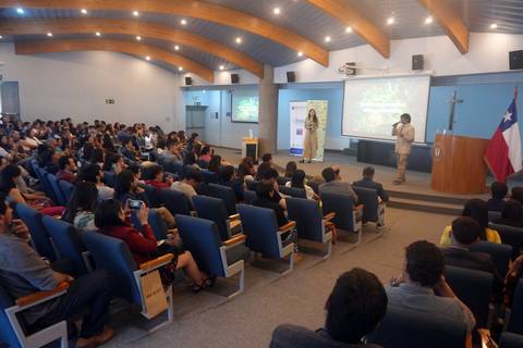 Un grupo grande de personas escucha atentamente a un expositor en una sala de conferencias.